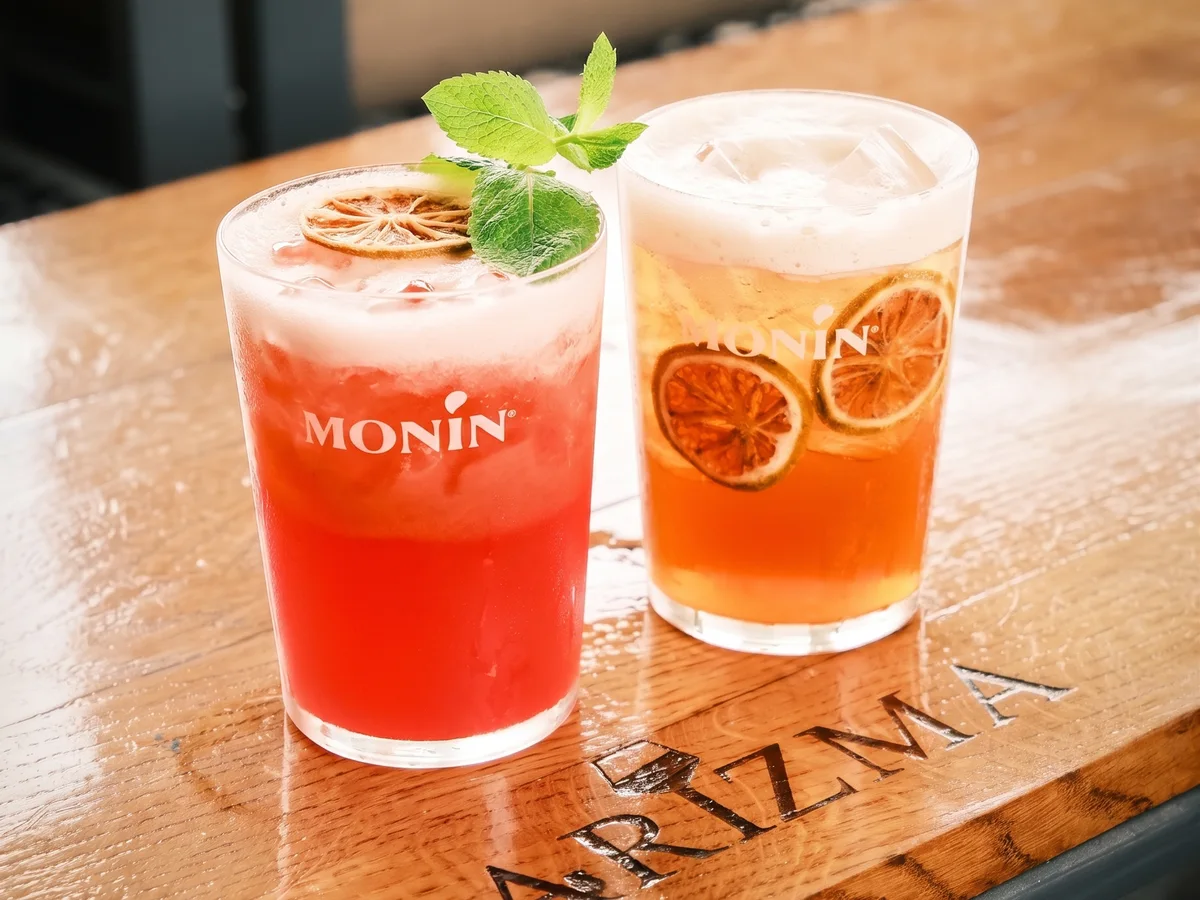 Karizma caffe bar Lanište Zagreb – dva koktela s Monin sirupima na brendiranom drvenom stolu
