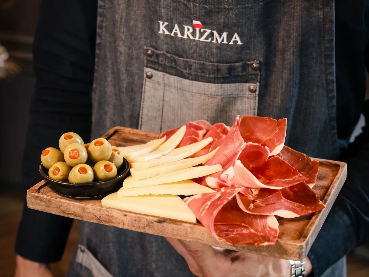 Karizma – konobar u pregači s drvenom daskom pršuta, sira i maslinki, Lanište Zagreb
