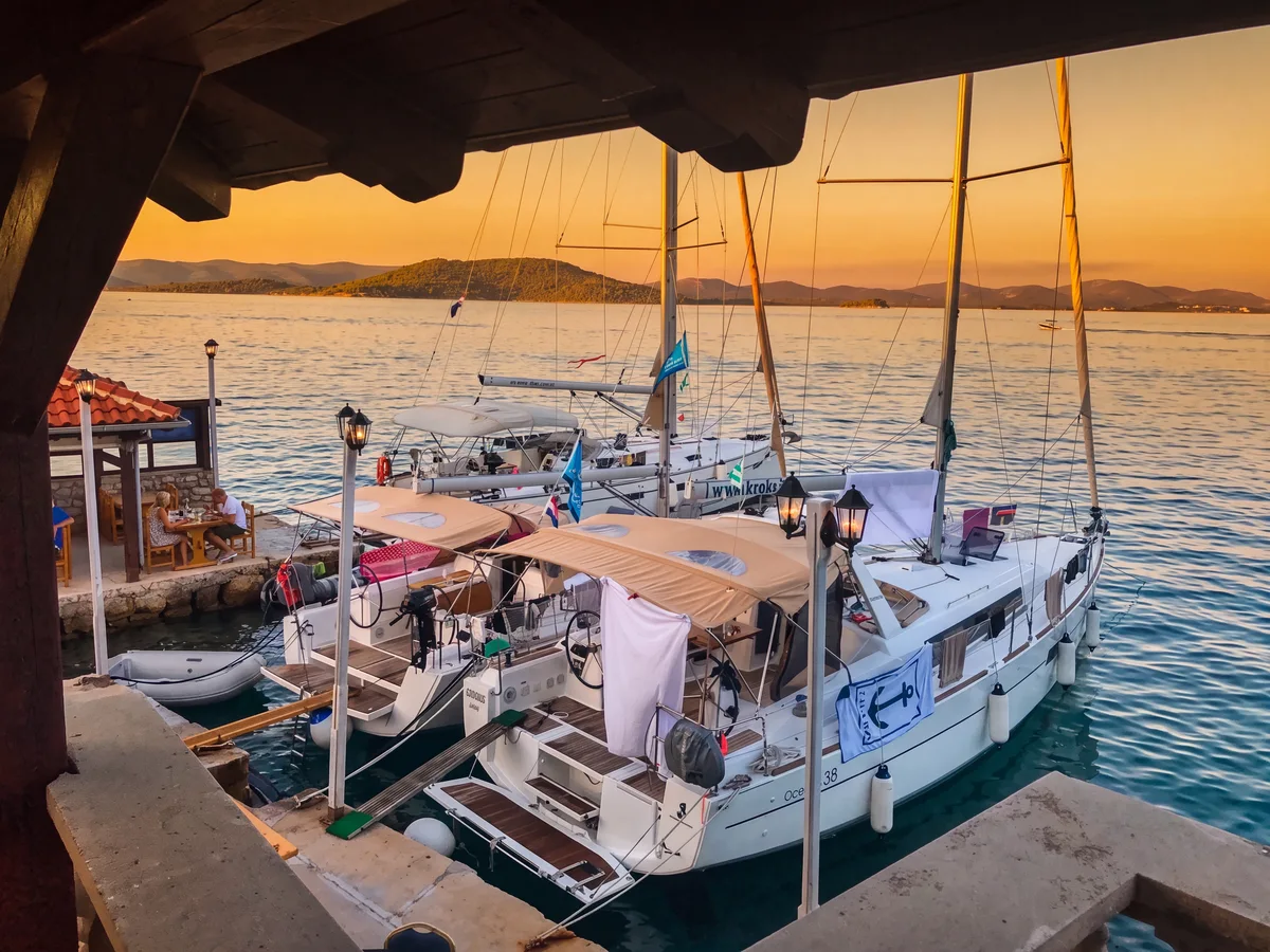 Trabakul Betina – wooden dock with sailboats at sunset, viewed from the restaurant terrace