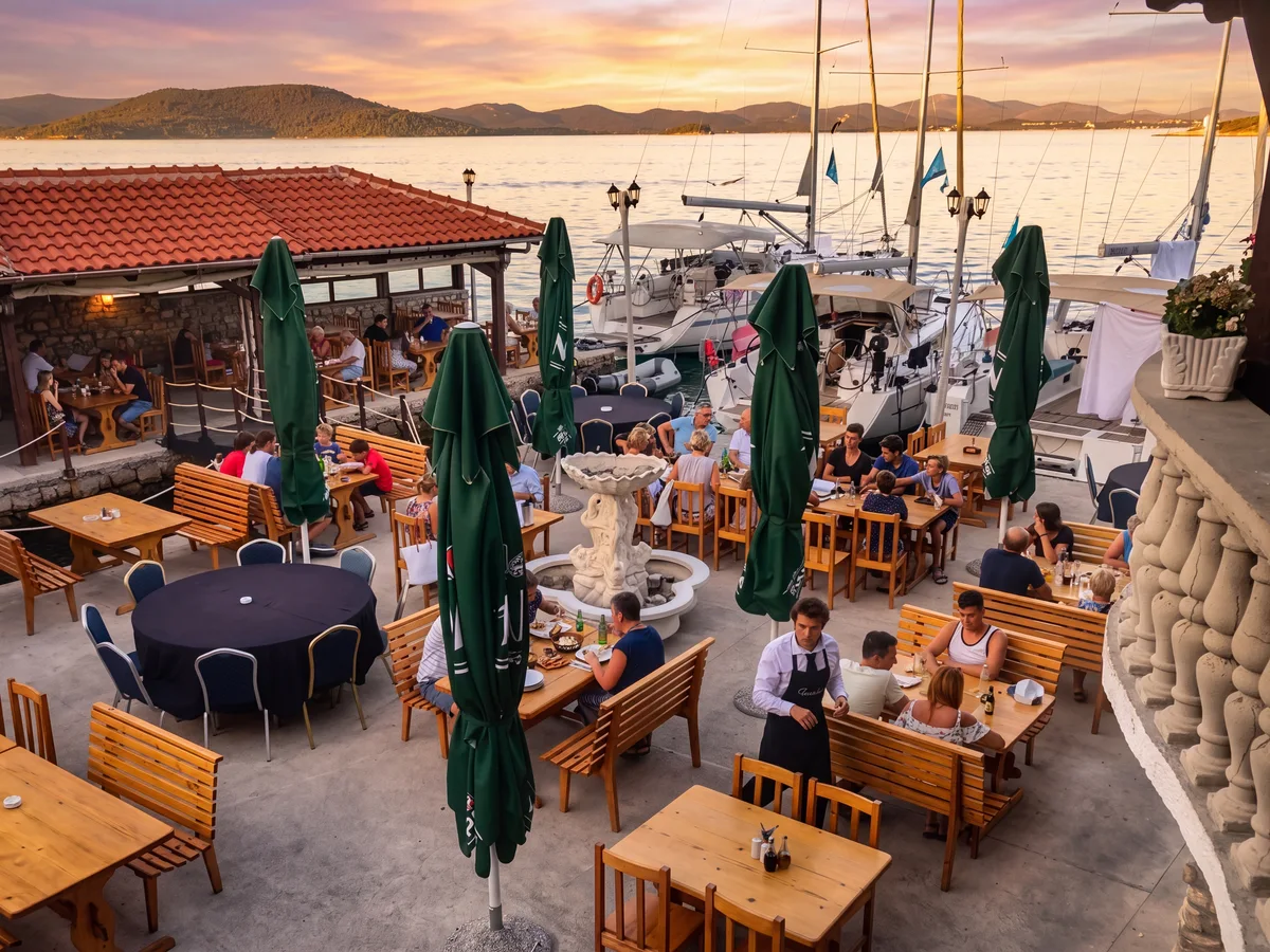 Trabakul Betina – guests on the terrace at golden hour with sailboats in the background, Murter